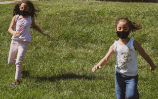 Anstieg von Kinderpornografie. Mädchen mit Maske laufen auf einer Wiese