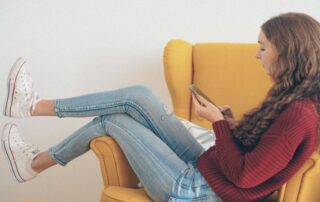 Bildschirmzeit. Mädchen mit Smartphone auf Sessel